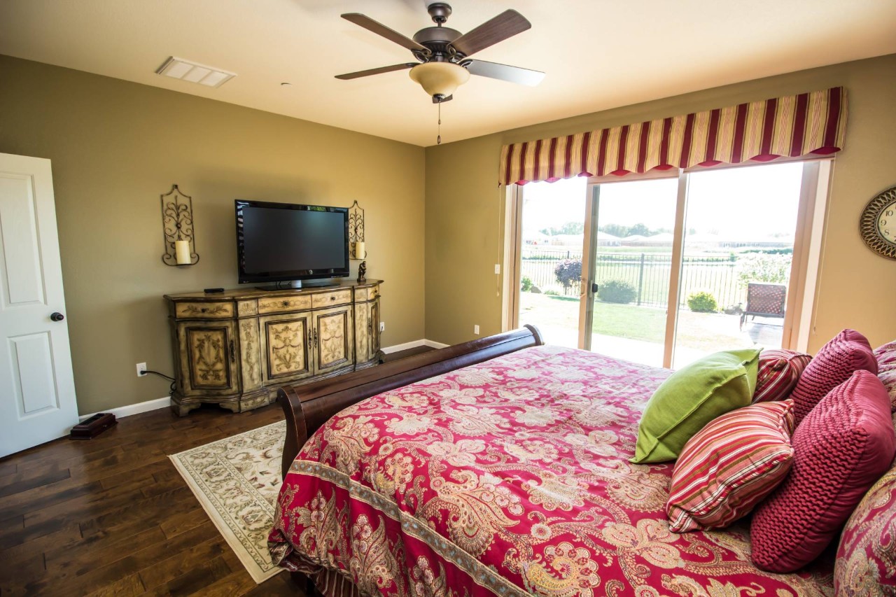 A valance over a sliding glass door in a bedroom featuring dark woods and reds at Dreamweaver Interiors & Fabrics near Rehoboth Beach, DE