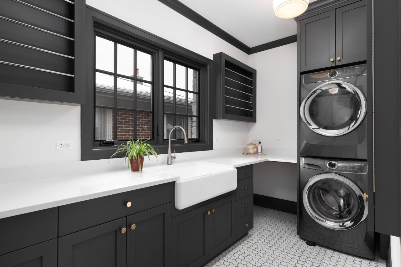 A trendy and modern laundry room with black cabinets, window trim, and a washer and dryer at Dreamweaver Interiors & Fabrics near Rehoboth Beach, DE
